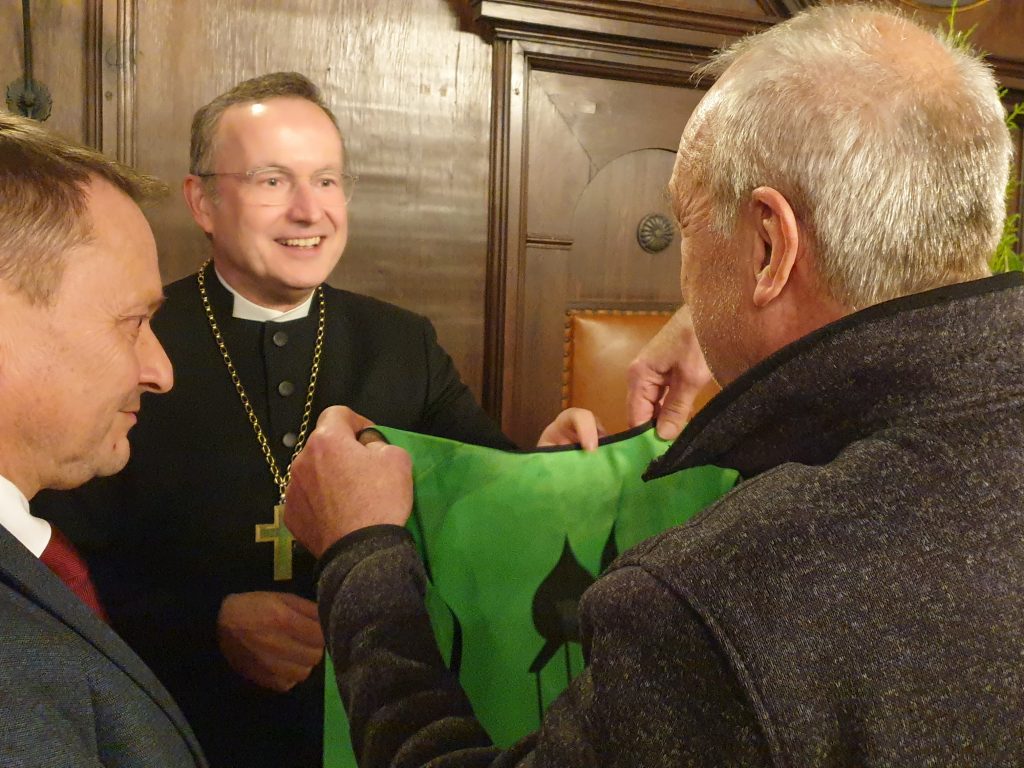 Der Landesbischof bekommt eine Radler-Weste überreicht.